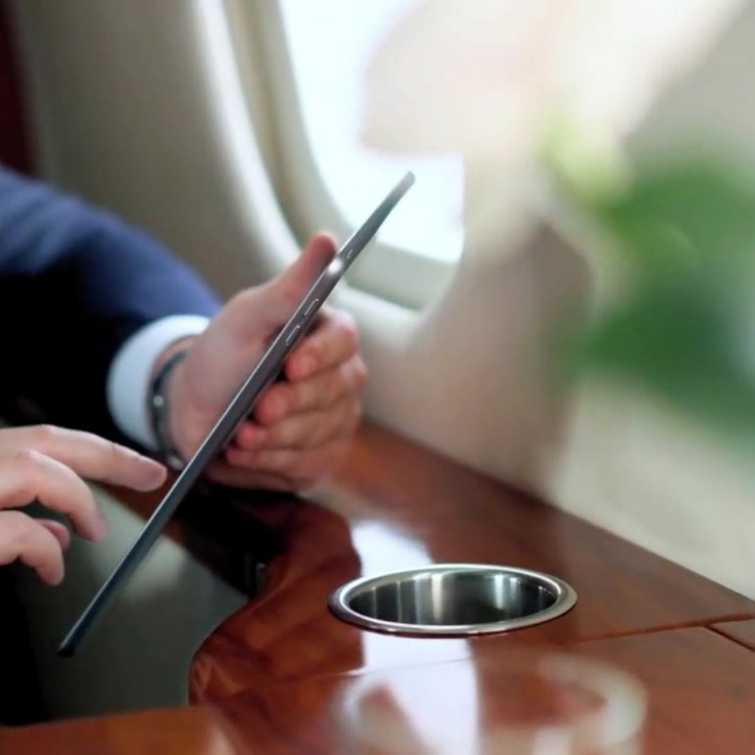 Business traveler relaxing in the cabin of a private jet while using a tablet.